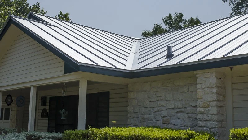 Home exterior with stone siding and newly installed standing seam metal roofing