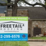 Image of a Freetail Roofing sign in front of a brick house with a newly installed roof in Burnet, TX