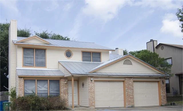 Excellent Residential Roof Replacements In Austin, TX | Freetail Roofing A tan and stone house with a new metal roof.