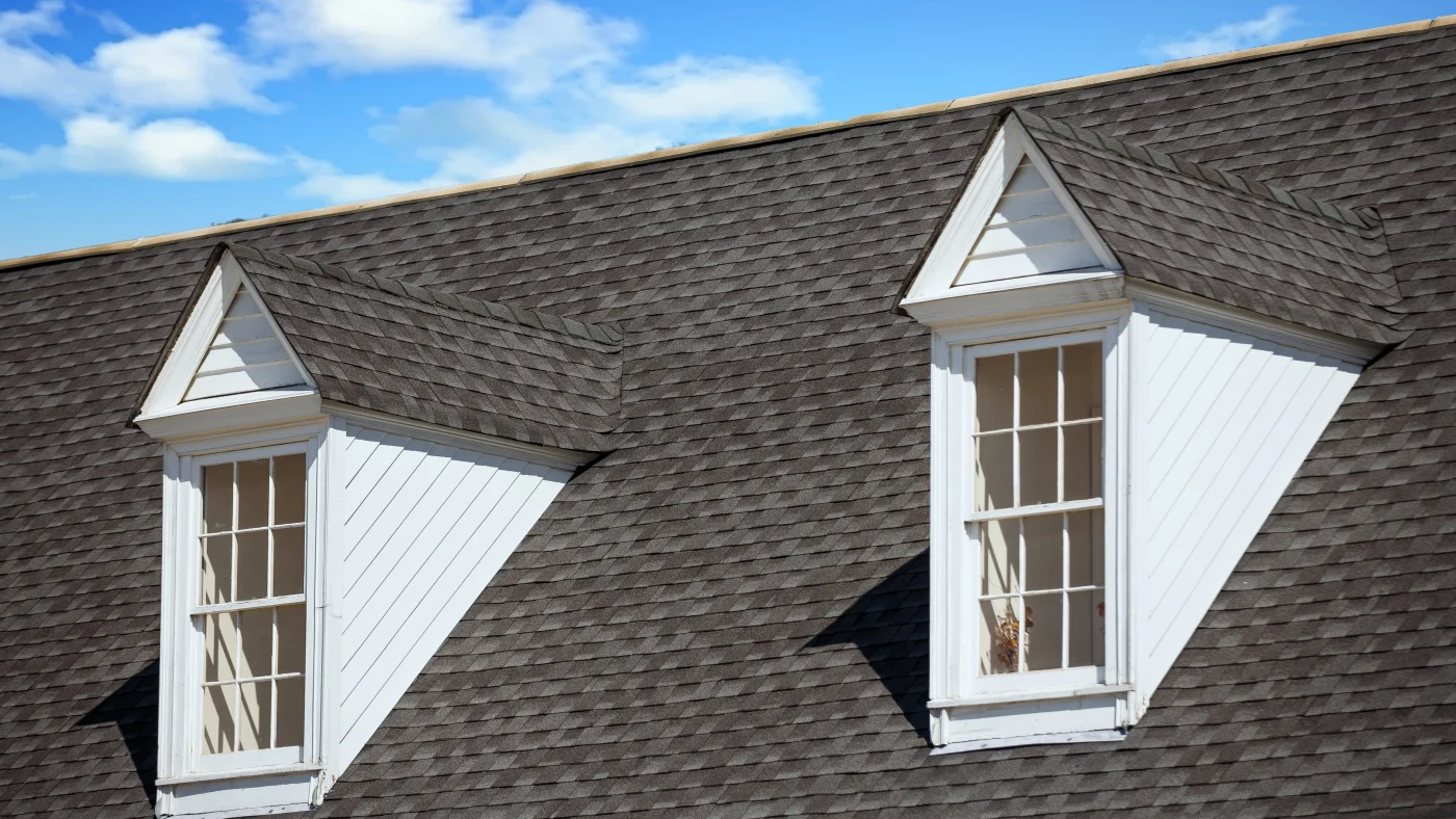 Gray asphalt shingle roof with two white dormer windows in Burnet, TX | Freetail Roofing