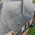 Close view of a shingle roof on a suburban home with damage spots indicated