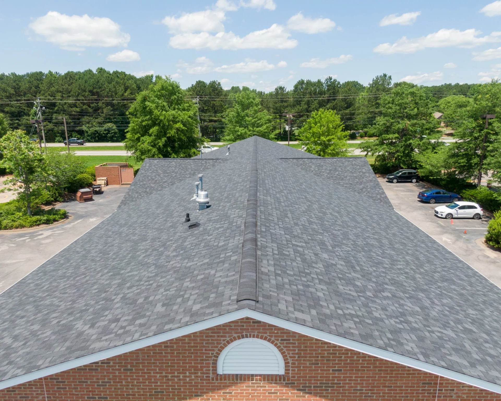 Aerial view of pristine gray asphalt shingle roof on brick building