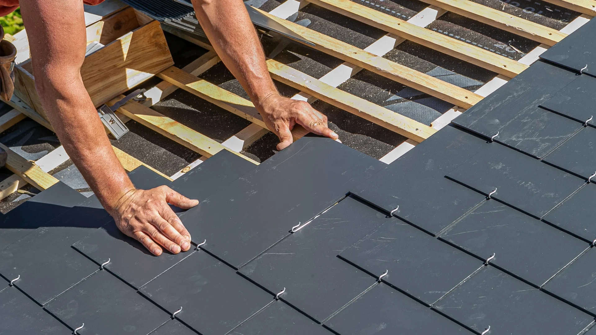 Close view of a roof installer putting a slate shingle into place in Oak Hill, TX | Freetail Roofing