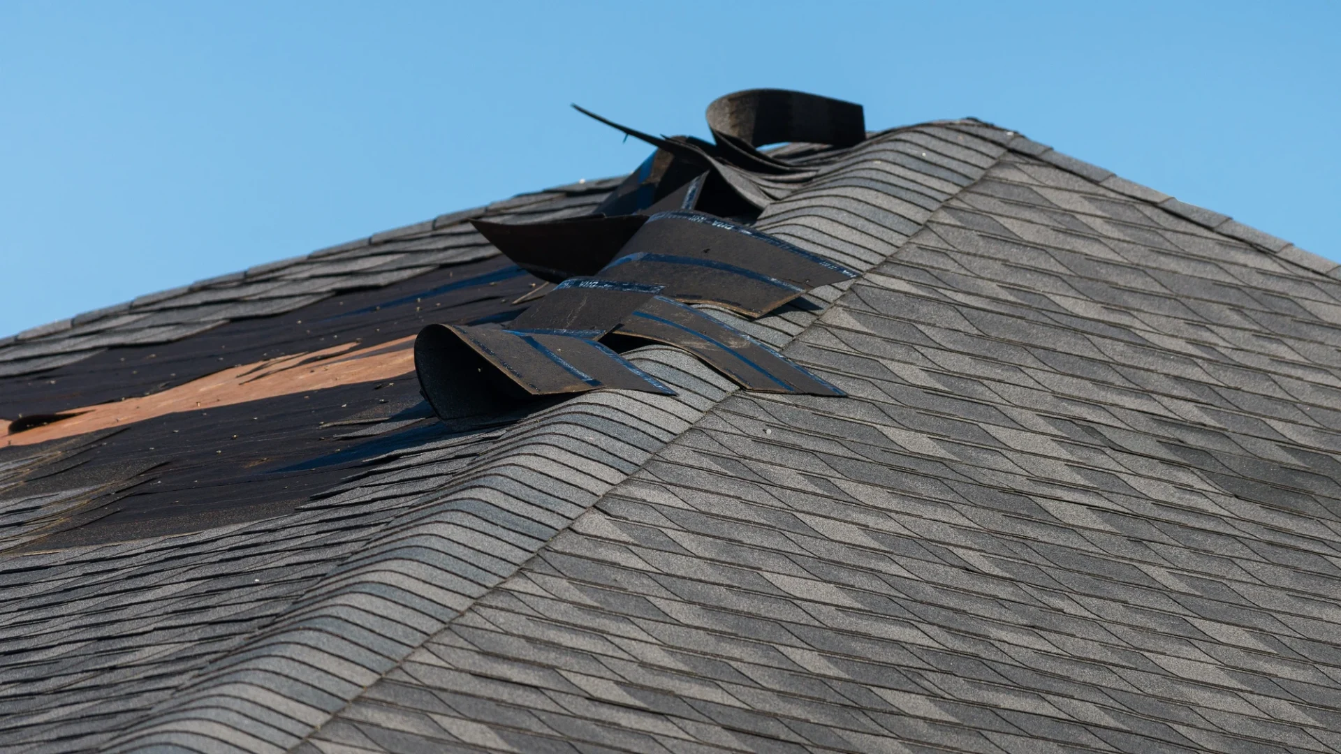 Detailed view of a section of storm-damaged asphalt roofing