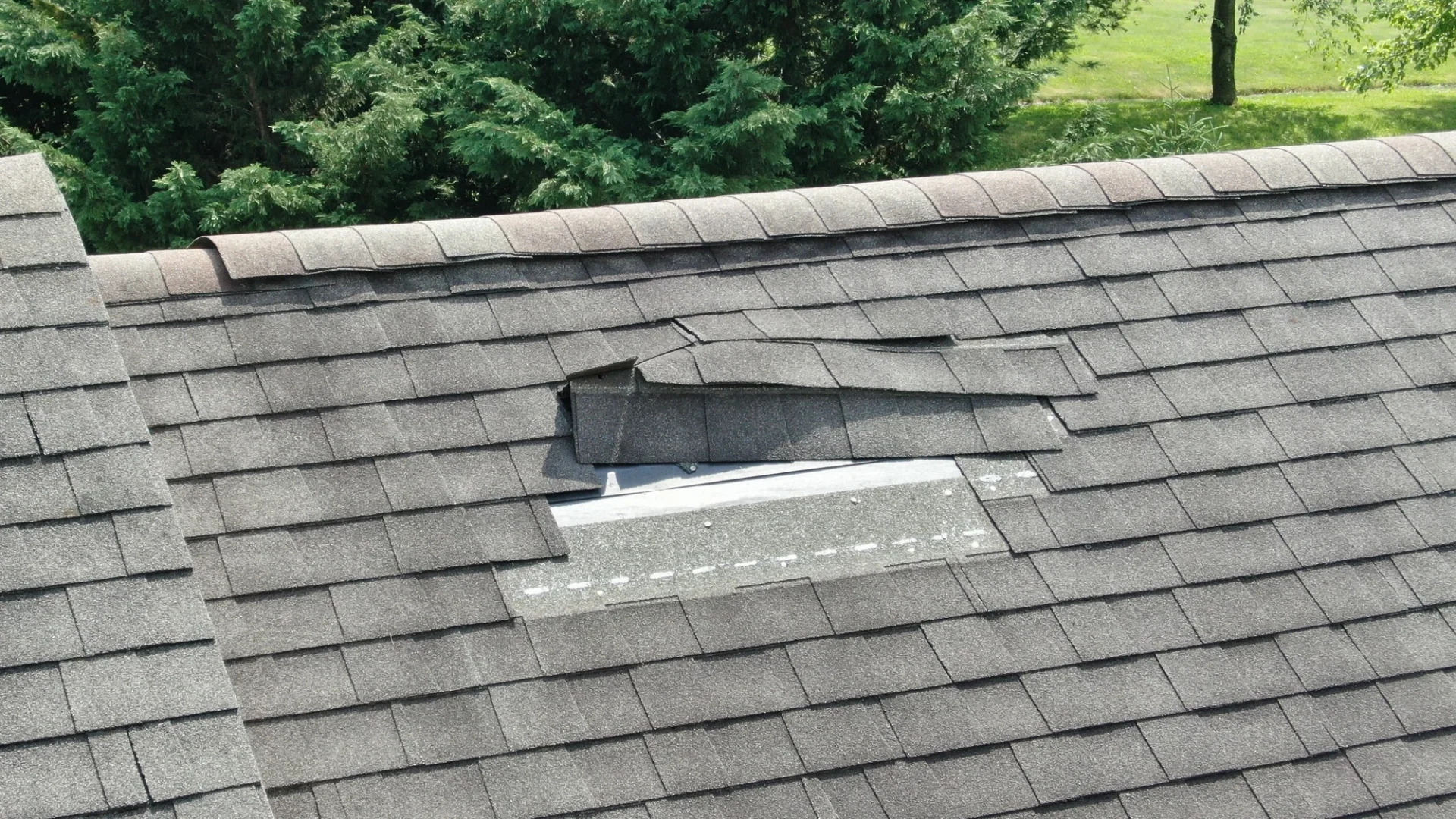 Elevated view of a damaged section of a residential asphalt roof