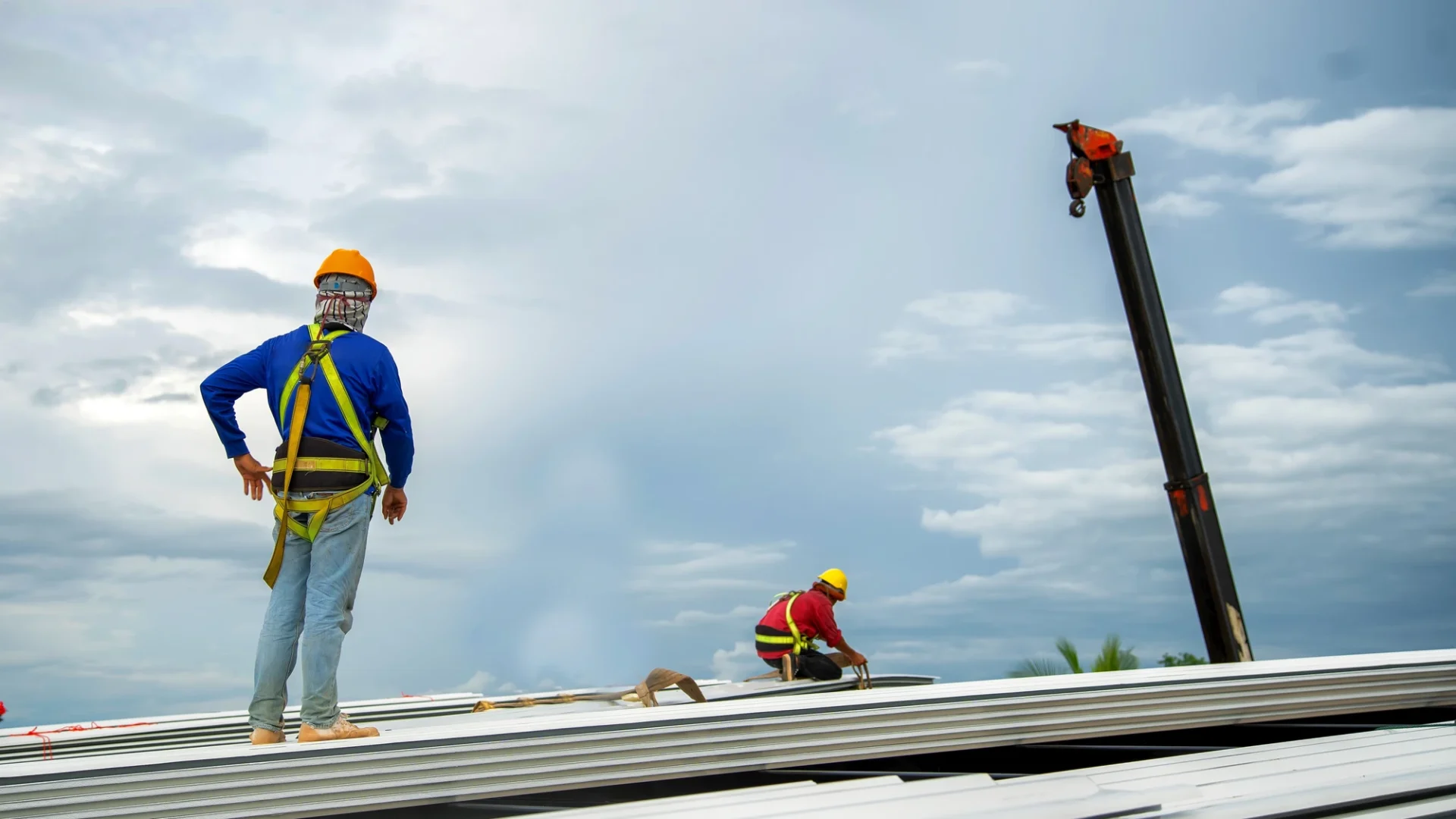 View of two roofers in the middle of installing a metal commercial roof