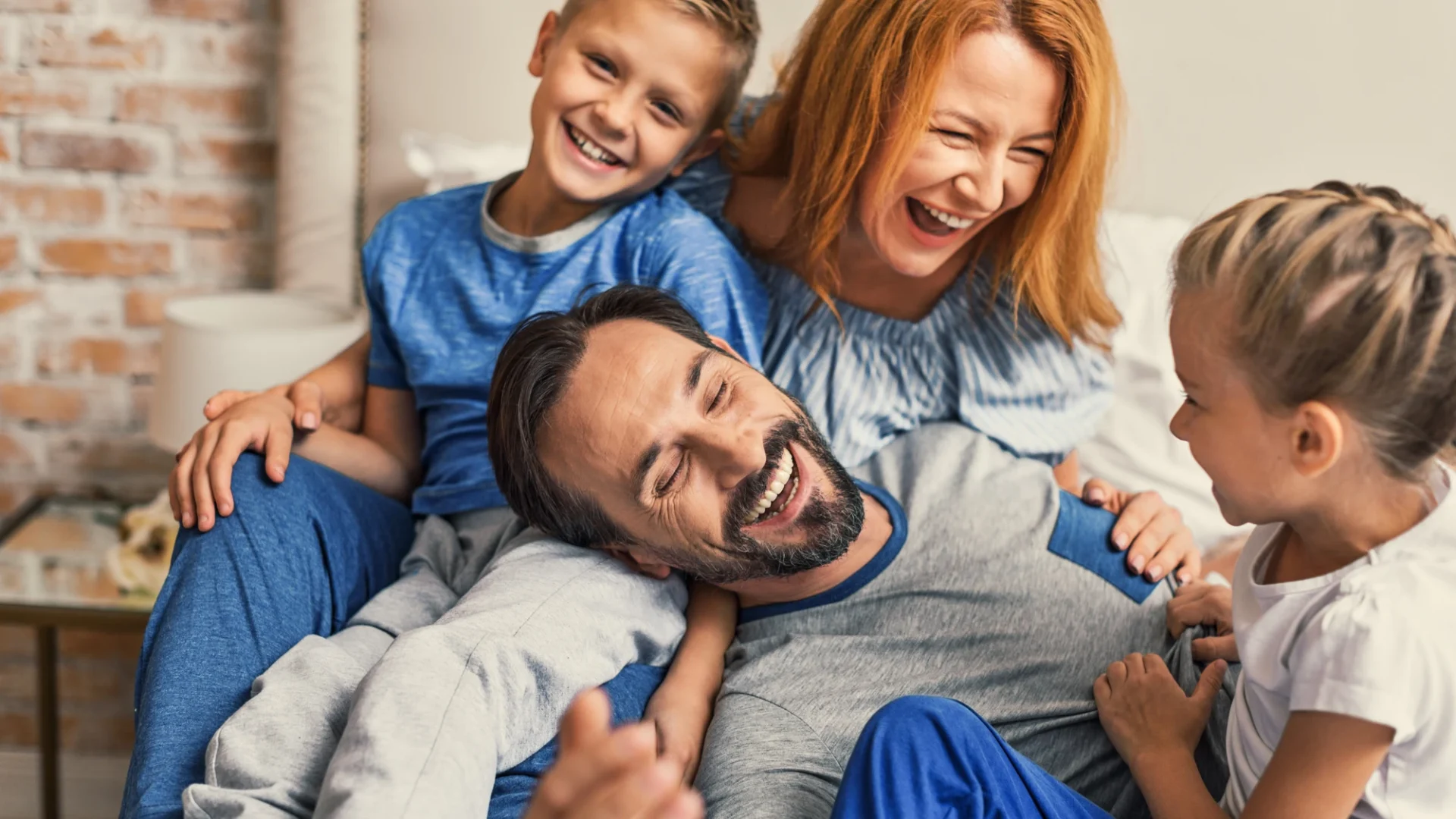 Family Oriented Culture And Superb Roofing Services Austin Tx Freetail Roofing A happy family of four laughing on a bed in their home