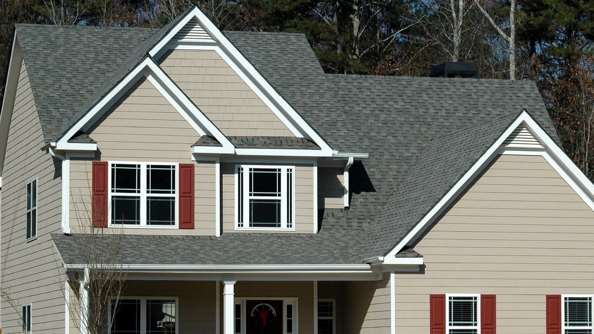 Close-up view of newly installed asphalt roofing on home with tan siding