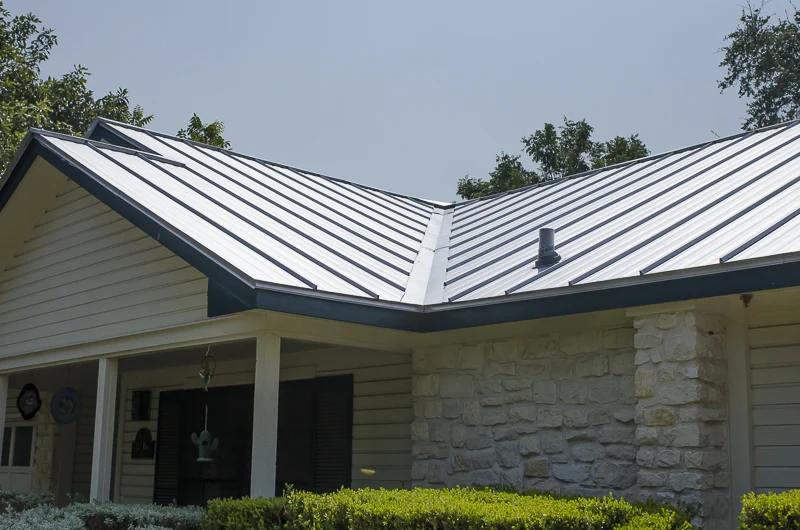 Roofing Option | Burnet,TX | Freetail Roofing Image of a house with stone siding and a metal roof in Burnet,TX | Freetail Roofing