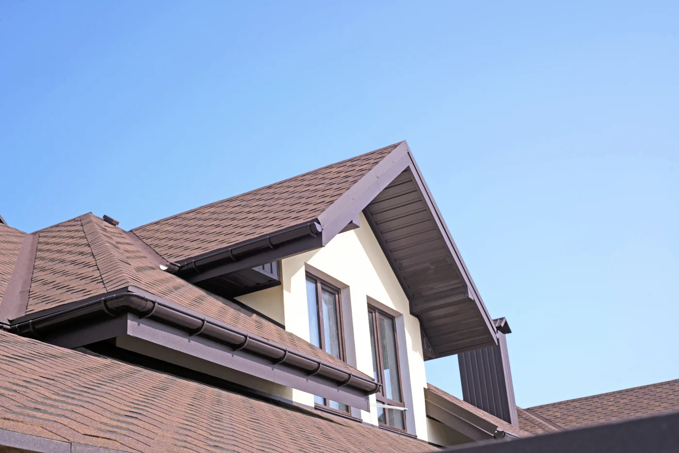Close-up of a house with new asphalt shingles on its roof.