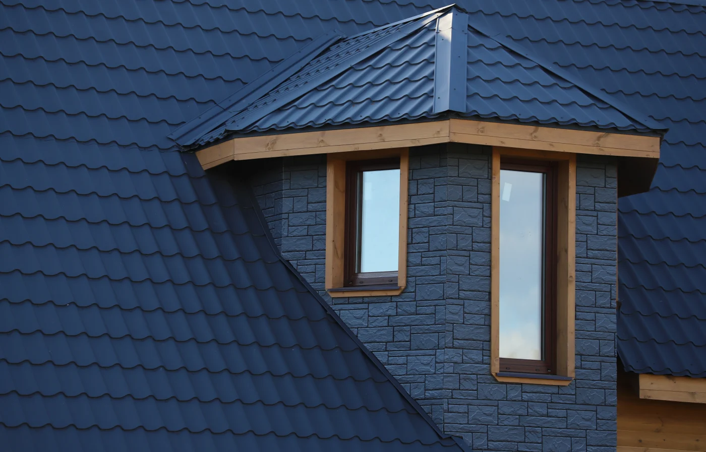 Premium Tile Residential Roof Replacements | Austin, TX | Freetail Roofing Close-up of a dormer featuring decorative stonework on a roof with rich, premium tile.