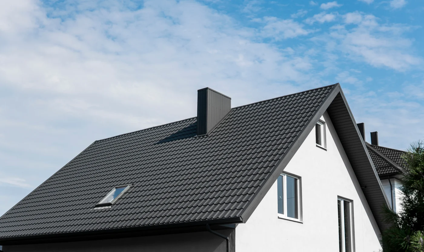Rich black tile on top of a large, white house in the suburbs.